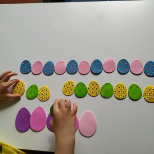 chłopiec układa piankowe jajka kolorowe w rzędach